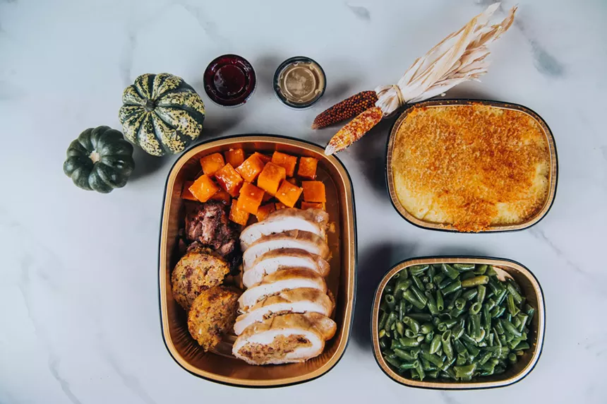 Three to-go containers from STK Steakhouse filled with turkey and other Thanksgiving sides