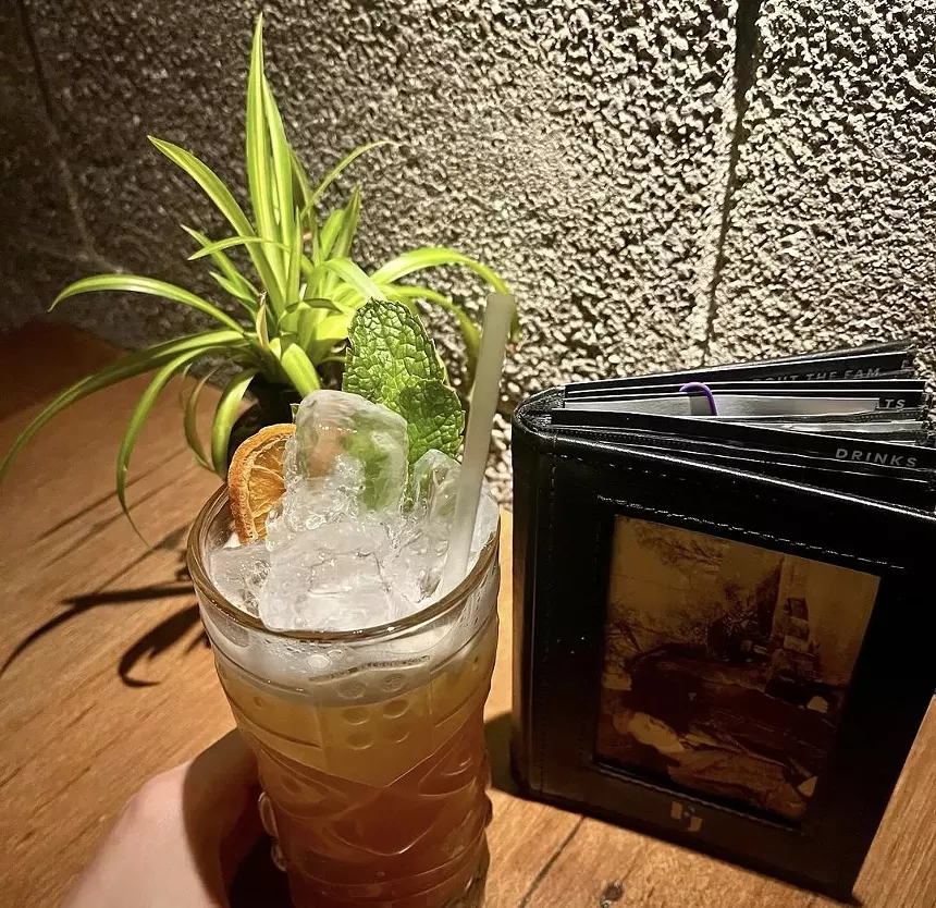a cocktail next to a menu on a table