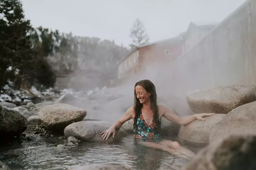 A woman soaking in a steamy creekside pool at Mount Princeton Hot Springs