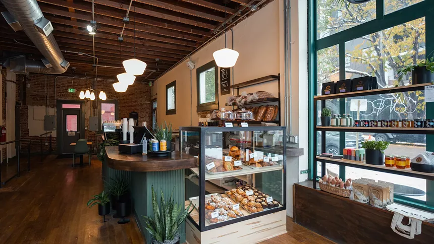 interior of a bakery and coffee shop with a pastry case at a counter