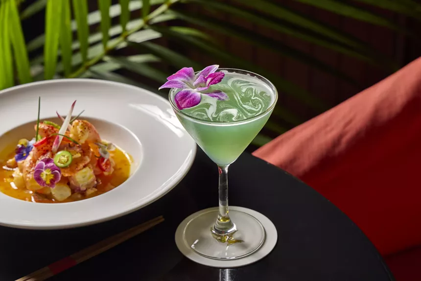 green cocktail garnished with a purple flower