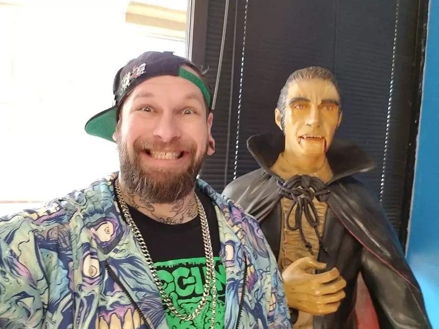 Brandon Riks standing next to a lifesize model of Dracula
