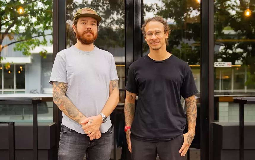 two men posing outside a building