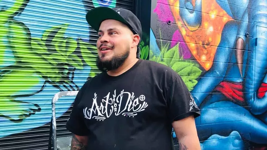 Markham Maes standing in front of one of his murals.