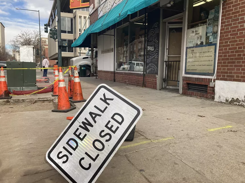 A sidewalk with a "sidewalk closed" sign overturned