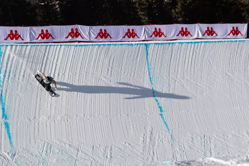 Snowboarder descends halfpipe
