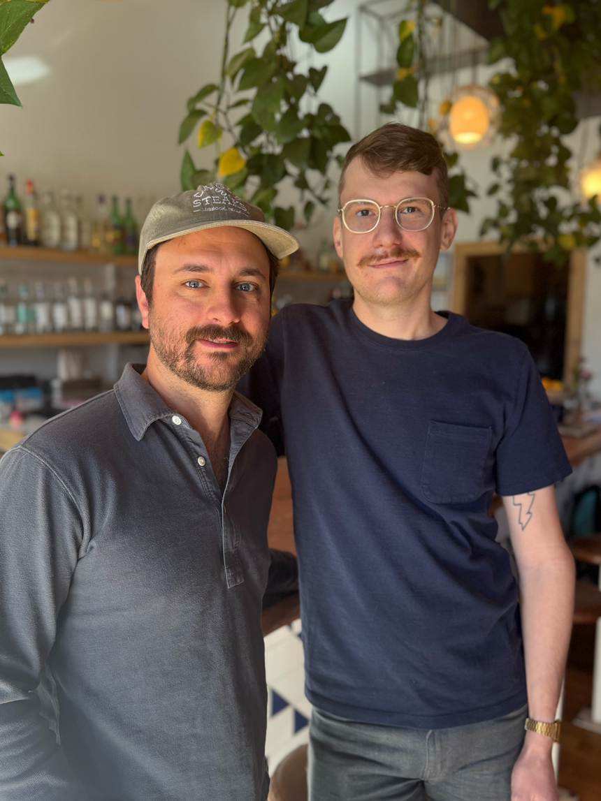 two men in front of a bar