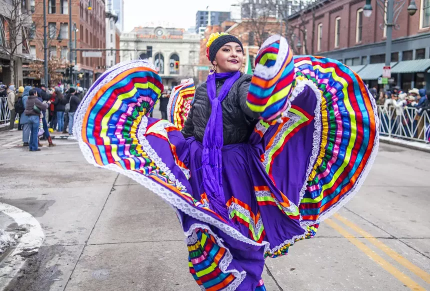 woman dancing in parade in purple Mexican dress.