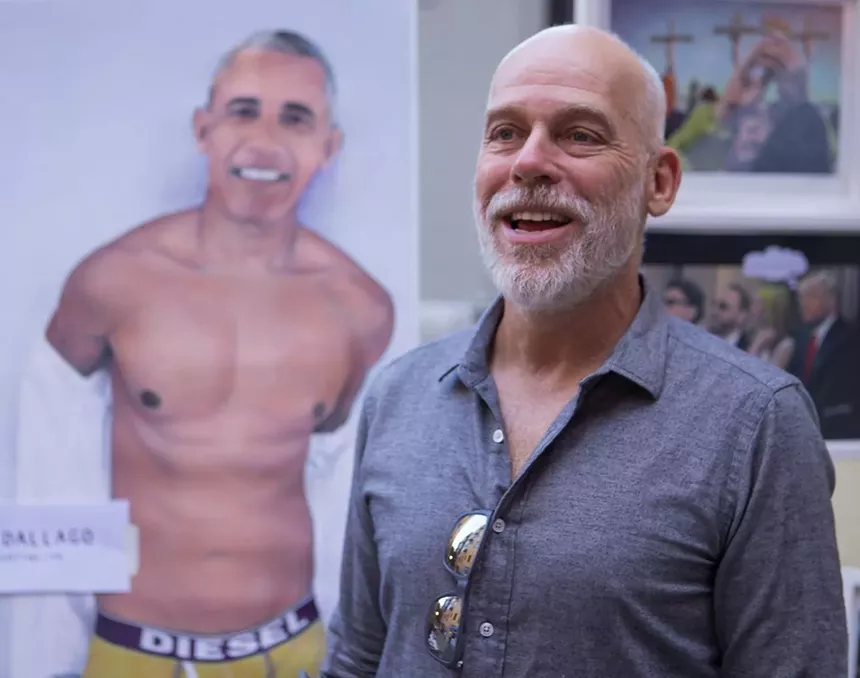 man in front of picture of Obama