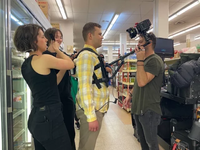 People assist a man in yellow get ready to film a scene.
