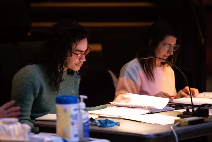 Two people sit at a table looking at scripts.