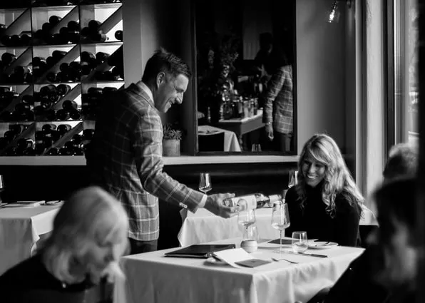 black and white photo of a person pouring wine