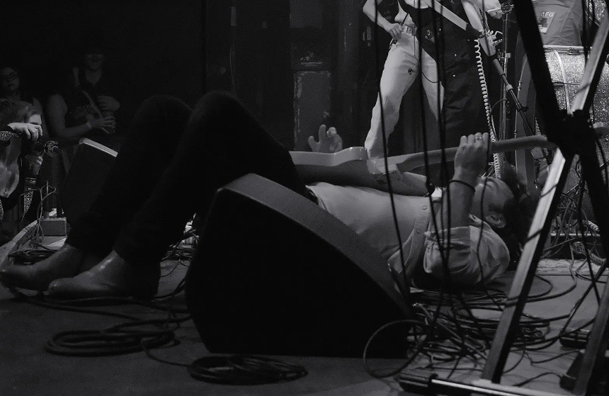 person playing guitar while lying on stage