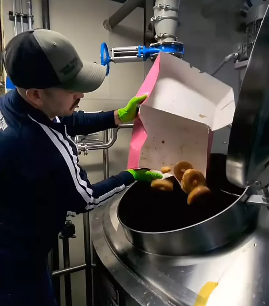 Brewer throwing donuts into a mash tun.