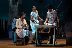 Three women around a wooden table.