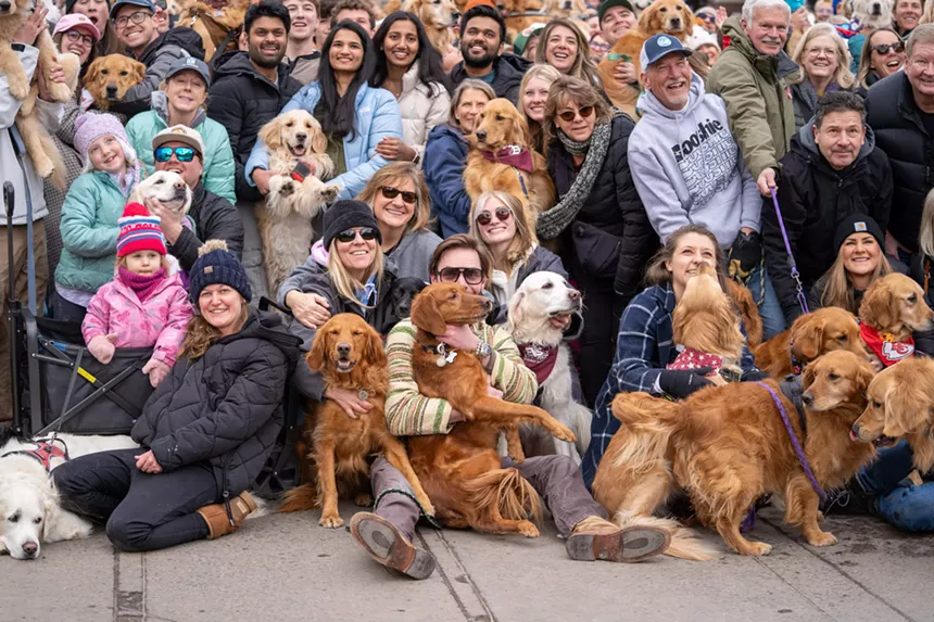 a group of people and their dogs smile for a photo
