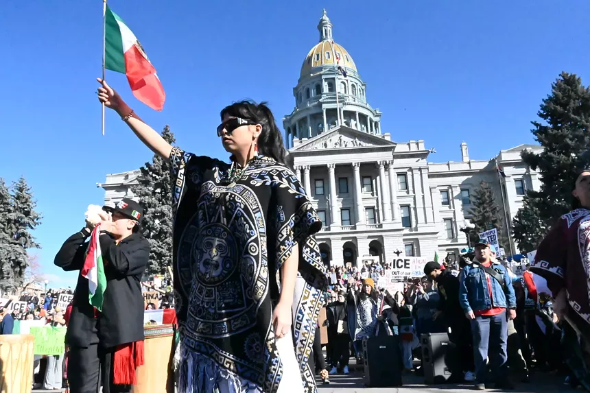 A woman raises a Mexican flag.