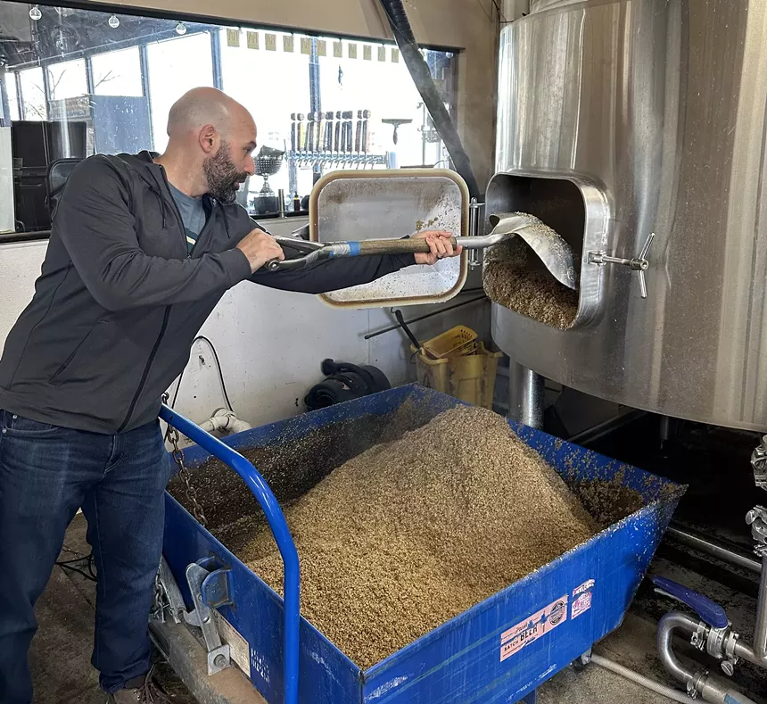 Man pulling grains out of a lauter tun.