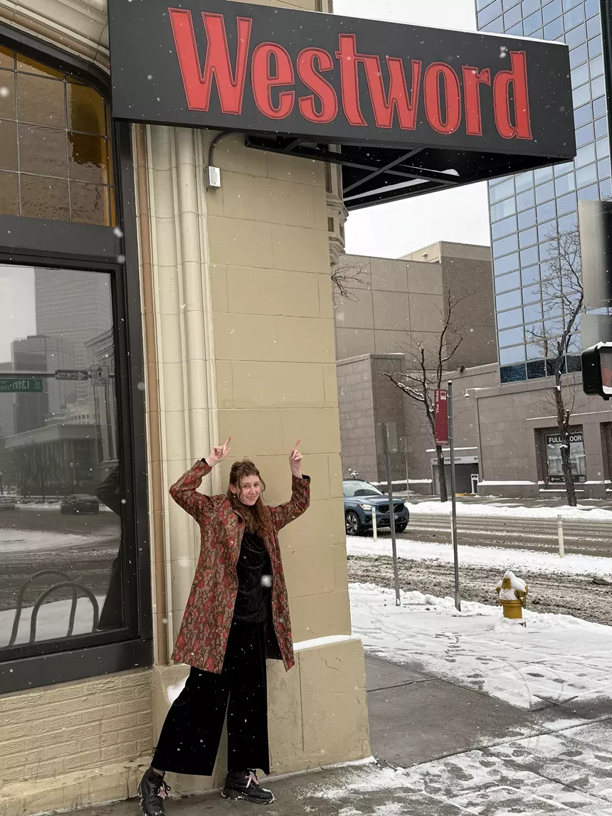 A person points at the Westword sign on the side of the Westword office building