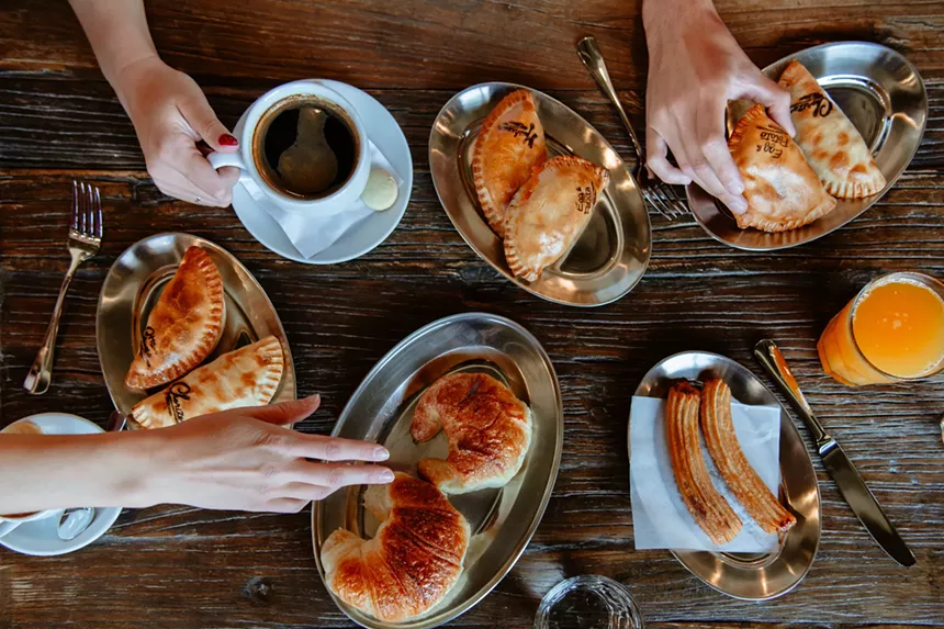 hands reaching for various empanadas and pastries