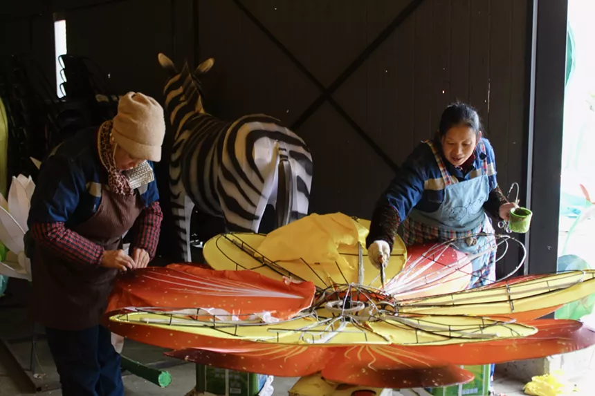 Two women work on a giant flower