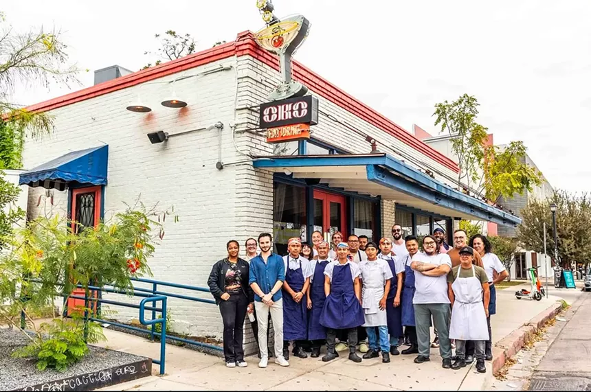 group of people posing in front of a restaurant