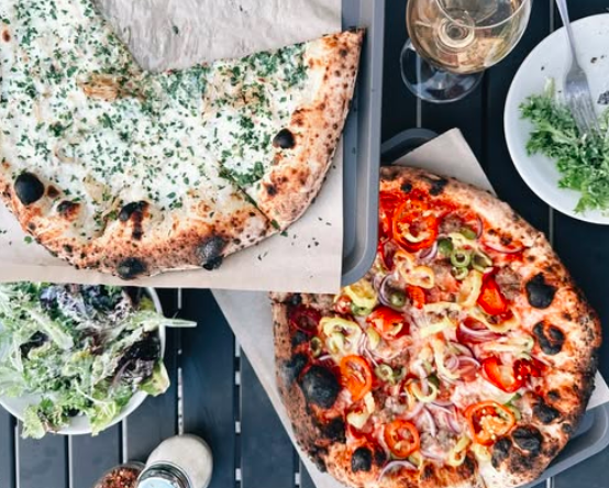 two pizzas and a salad on a table