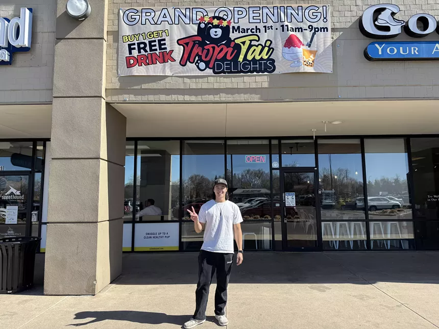 man posing in front of a strip mall shop