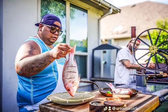 man holding a fish over a grill