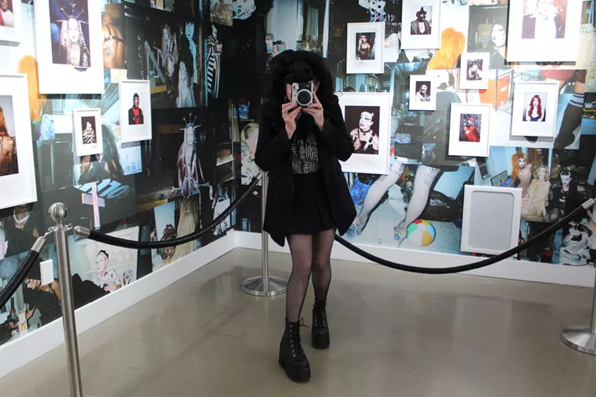A woman dressed in black takes an instant photo