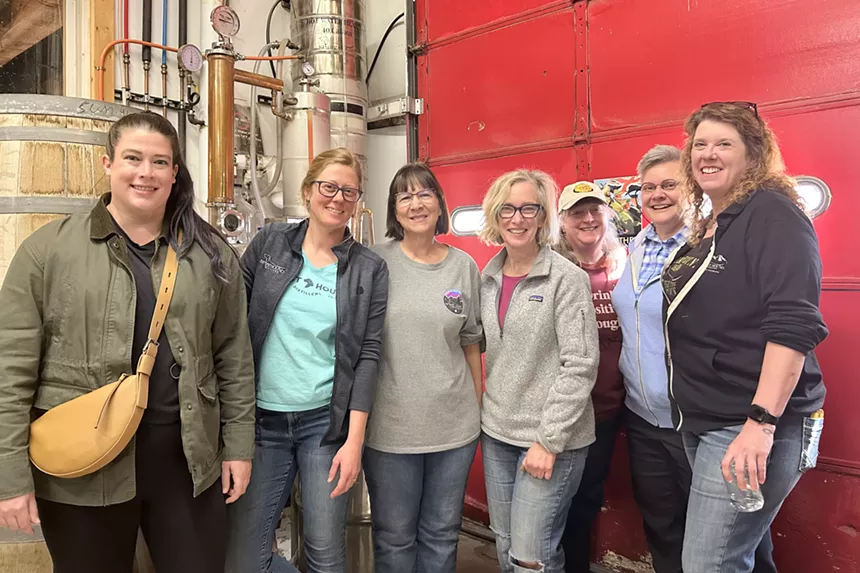 A group of women, dubbed the Whisky Wenches, backdropped by Spirit Hound distillation equipment
