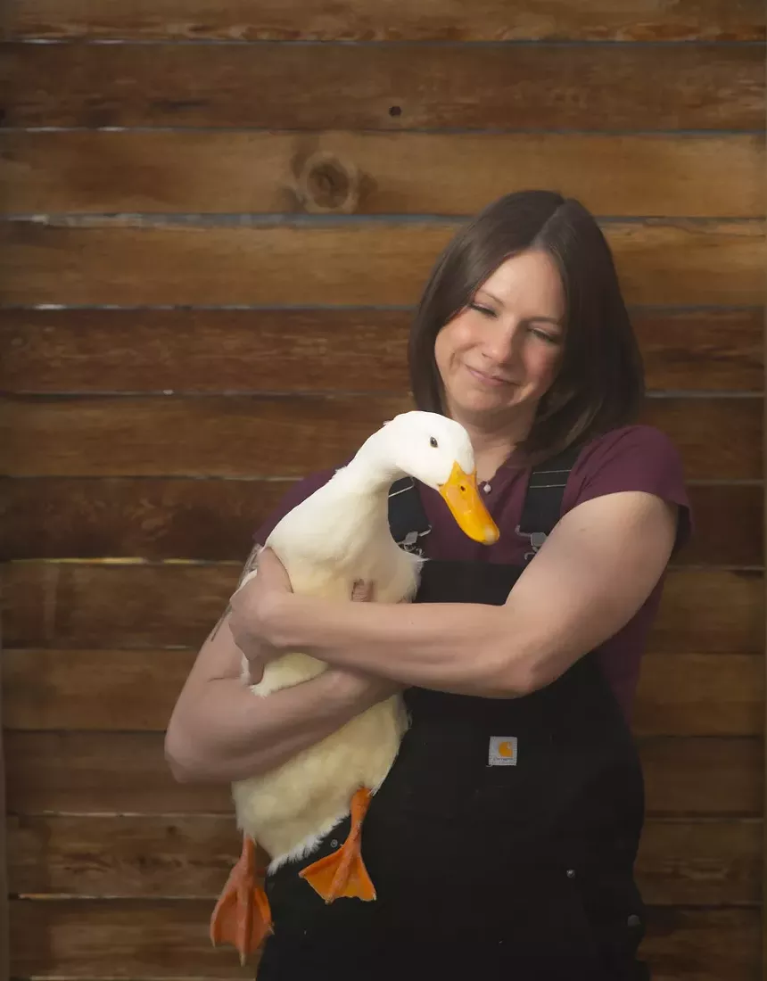 Woman with duck against wood wall