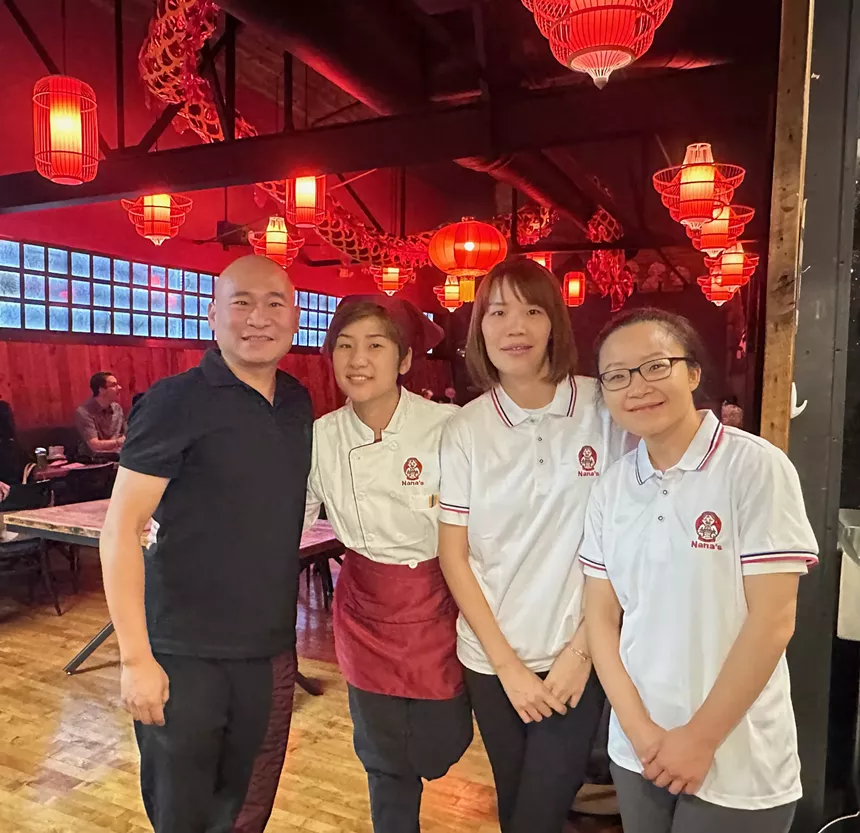 four people posing inside a restaurant with red lanterns
