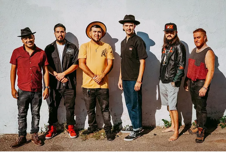 A group of mean leans against a wall.