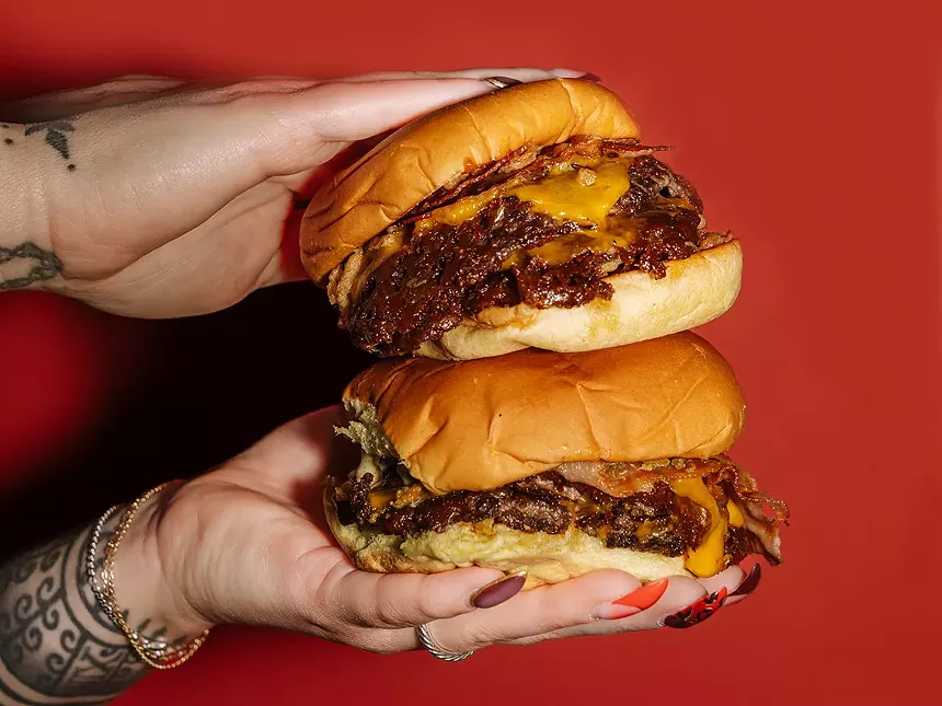 hands holding two smashburgers