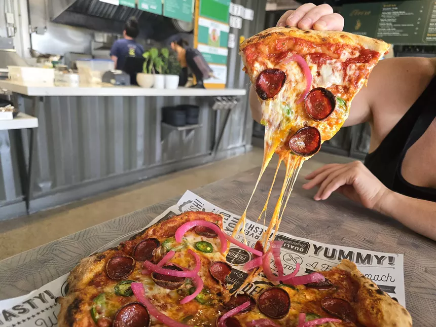 hand lifting a slice of pizza