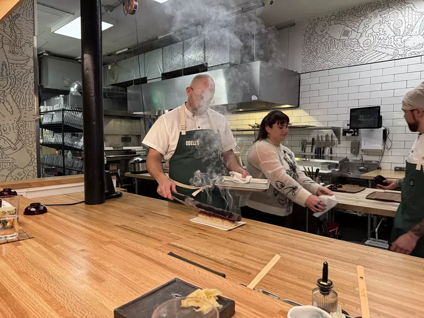 chef behind counter with burning branch