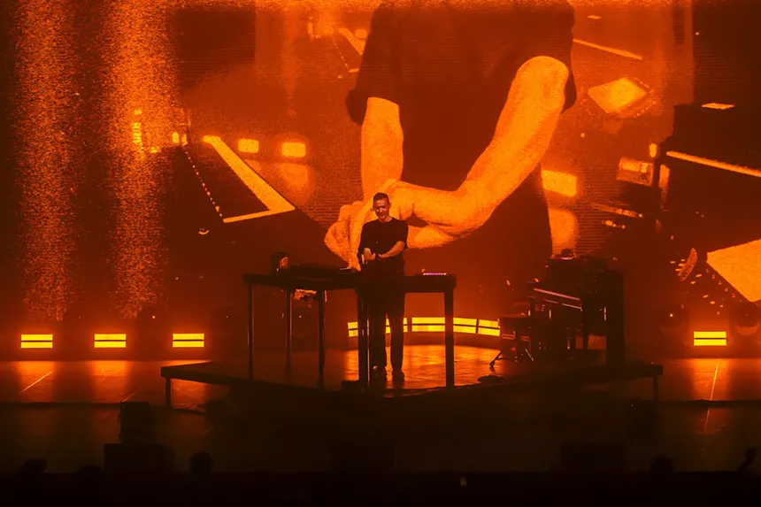 A photo of Ben Böhmer performing against an image wall displaying himself performing to the crowd.