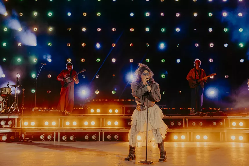 Remi Wolf on stage with stage lights behind her.