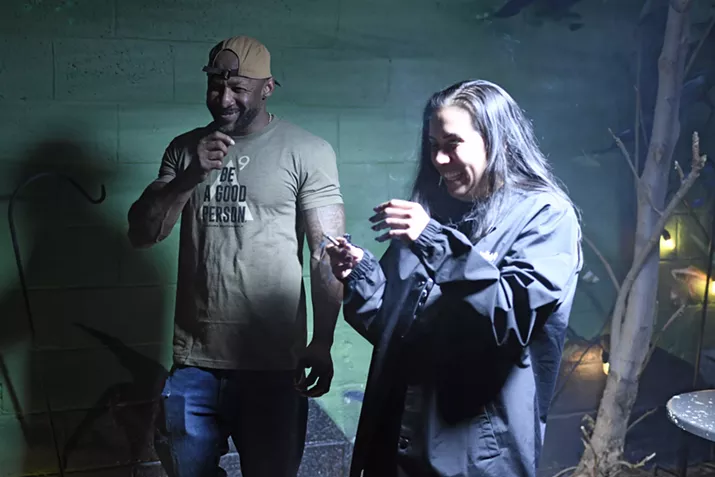 Two people smoke a joint together