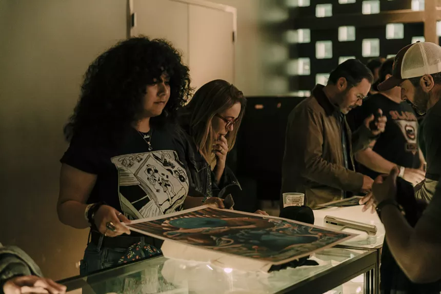 A photo of a concertgoer at the merch booth looking at a Sturgill Simpson tour poster.