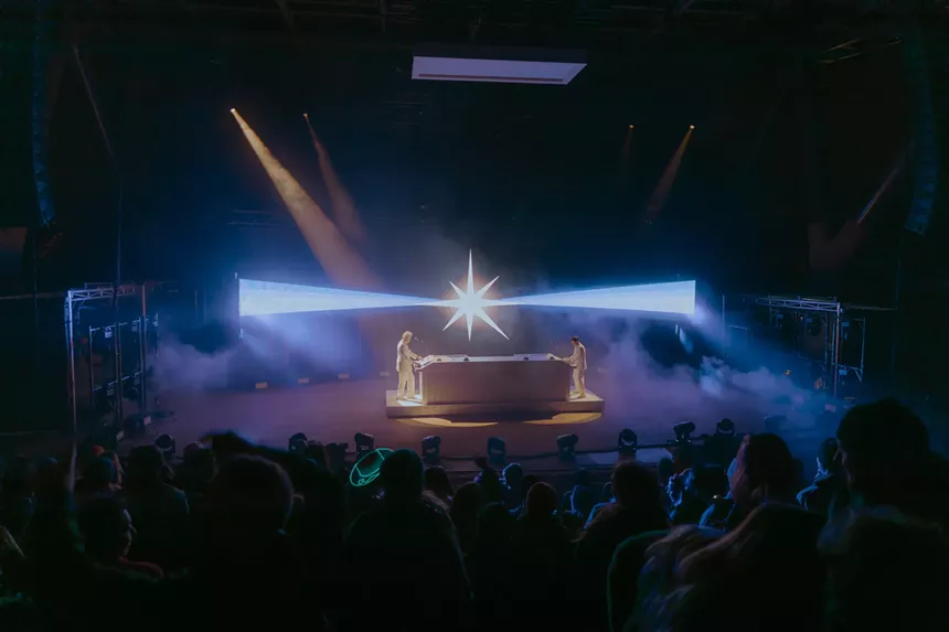 Polo & Pan performing on stage with visuals showing in the background.