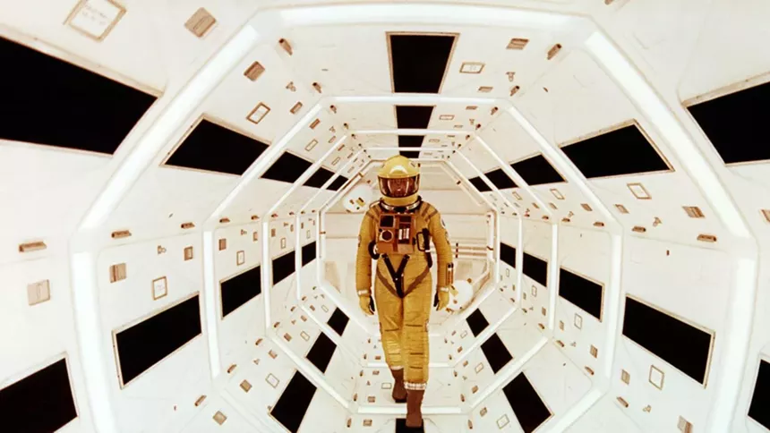 An astronaut walks through a black and white hall