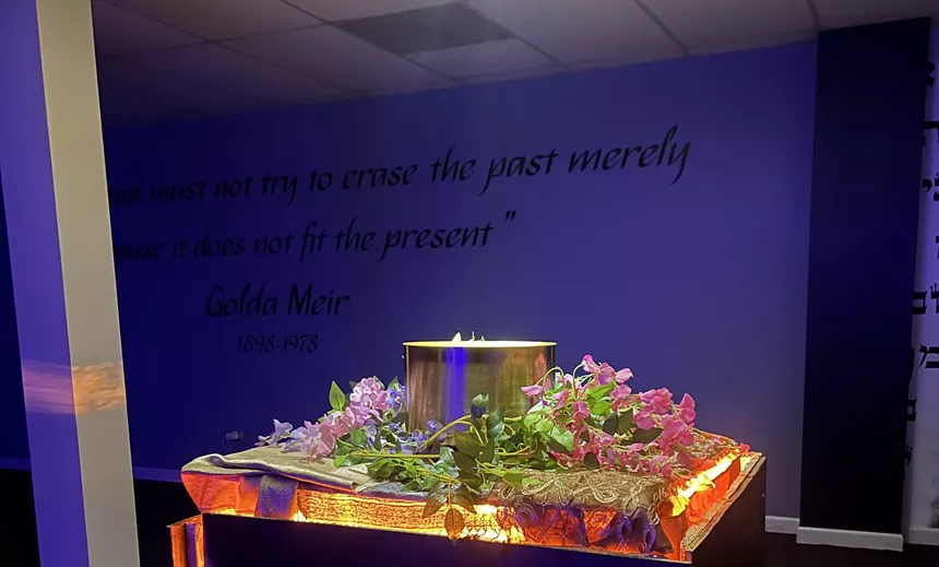 An altar with black cursive words behind it about not forgetting the past.