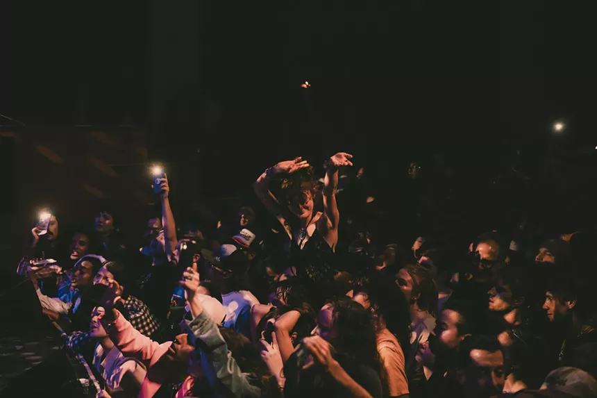 A photo showing a concertgoer dancing while on the shoulders of another at the Bluebird Theatre.