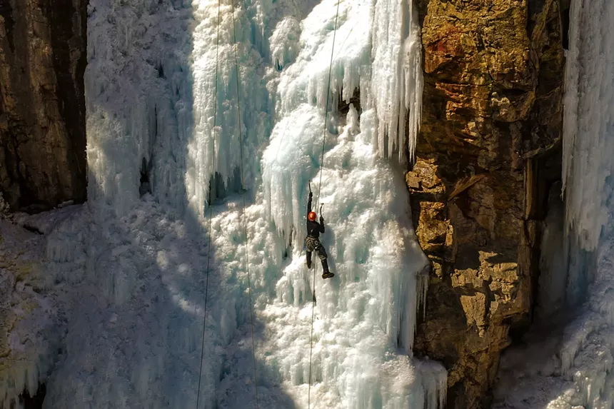 An ice climber scaling a frozen cliff in Ouray