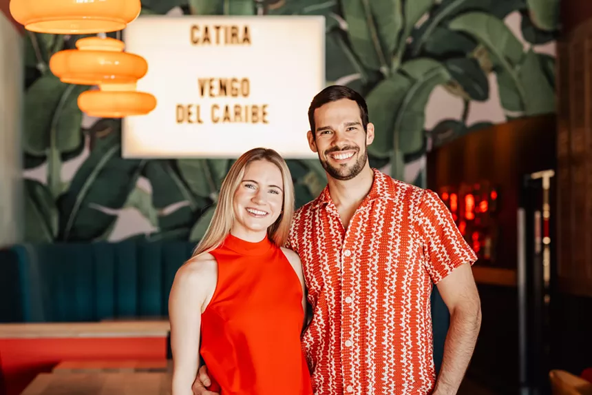 man and woman in front of restaurant sign
