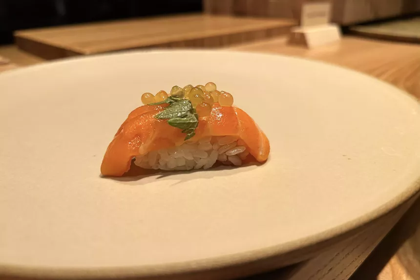 A piece of sushi featuring salmon and golden trout roe