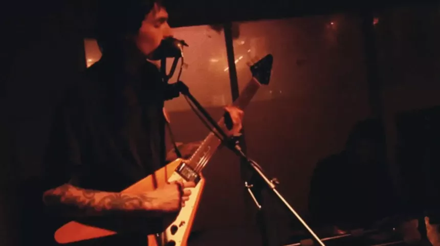 A person playing a guitar and singing into a microphone.