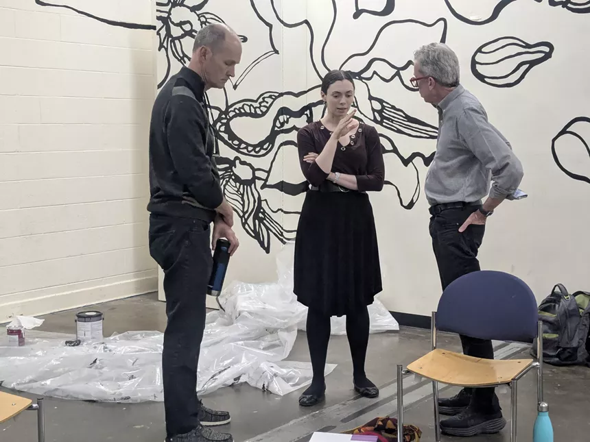 Three people stand in a circle and talk.
